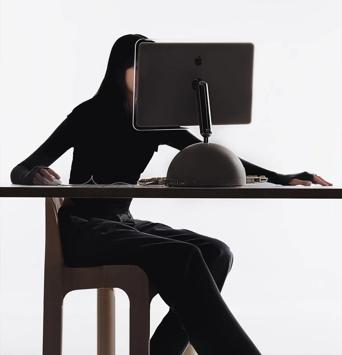 A person working at a desk, monitor silhouetted against white