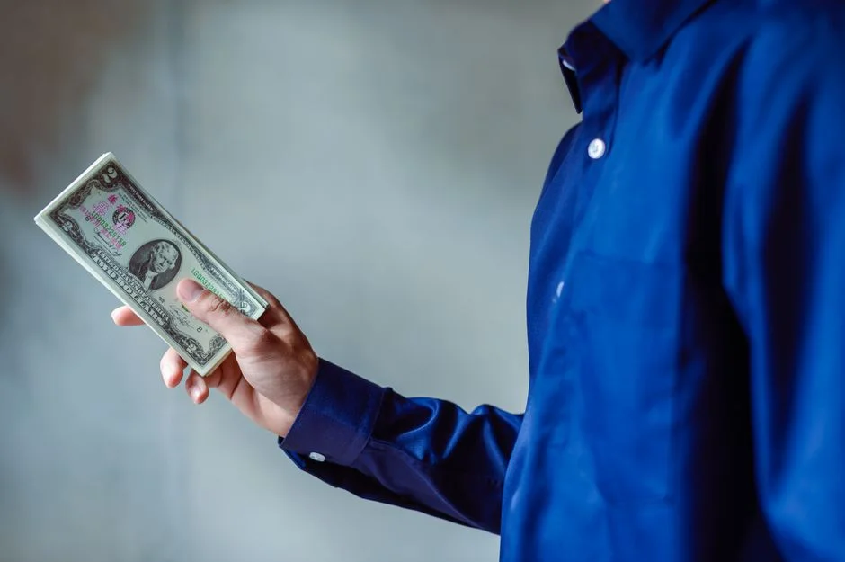 {'image_alt': 'Professional holding a stack of US dollar bills, symbolizing competitive GTM engineer salaries in 2026.'}