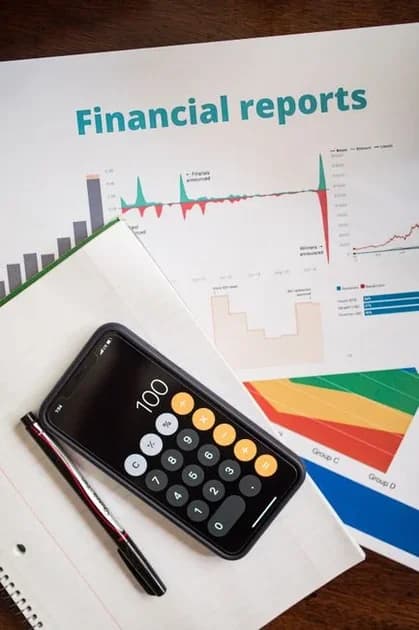 Top-down view of financial documents beside a smartphone calculator, illustrating cost analysis for SaaS go-to-market au