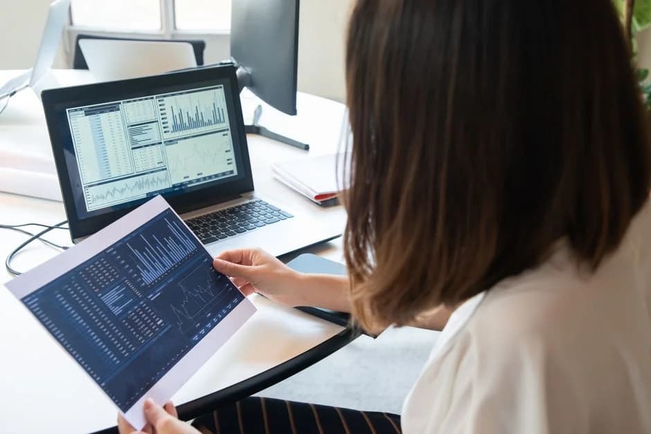 Professional woman reviewing financial charts and data on her laptop for business analysis.