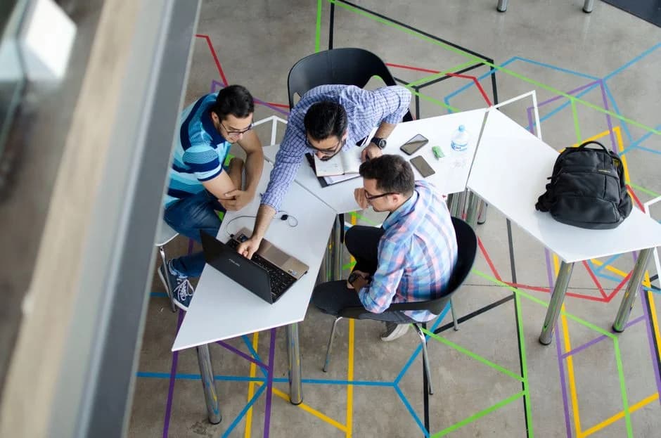 Team of three entrepreneurs collaborating over a laptop in a modern office, planning go-to-market strategy