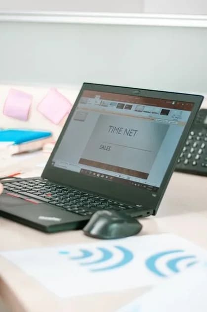 Laptop on a desk showing a sales presentation with charts and graphs on the screen.