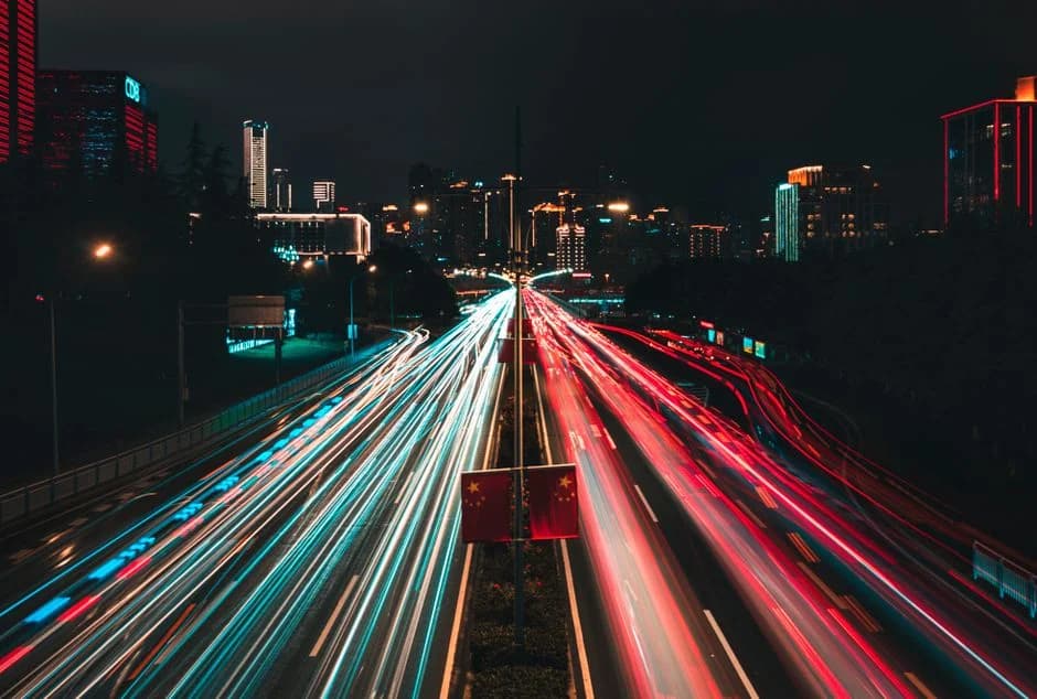 Black and white long exposure photo of streaking vehicle lights on a busy highway, capturing the energy and motion of ci
