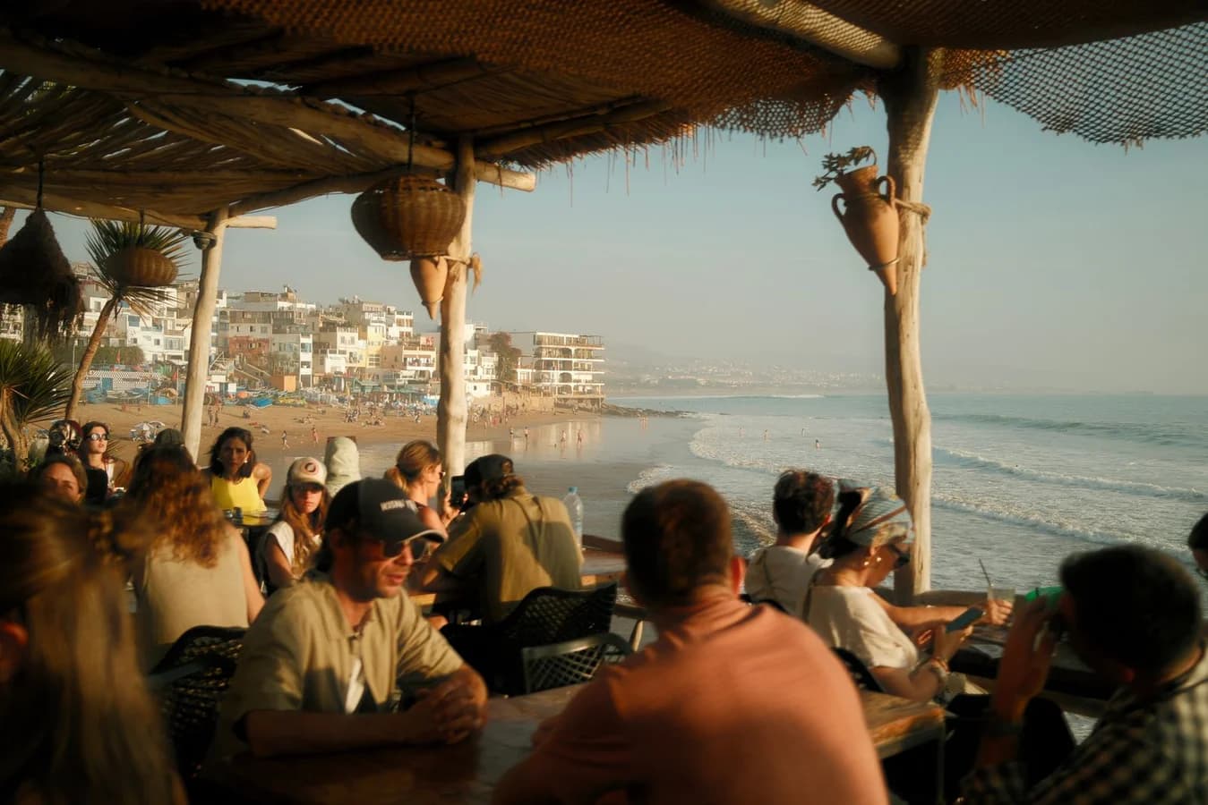Guests at a seaside cafe terrace at sunset