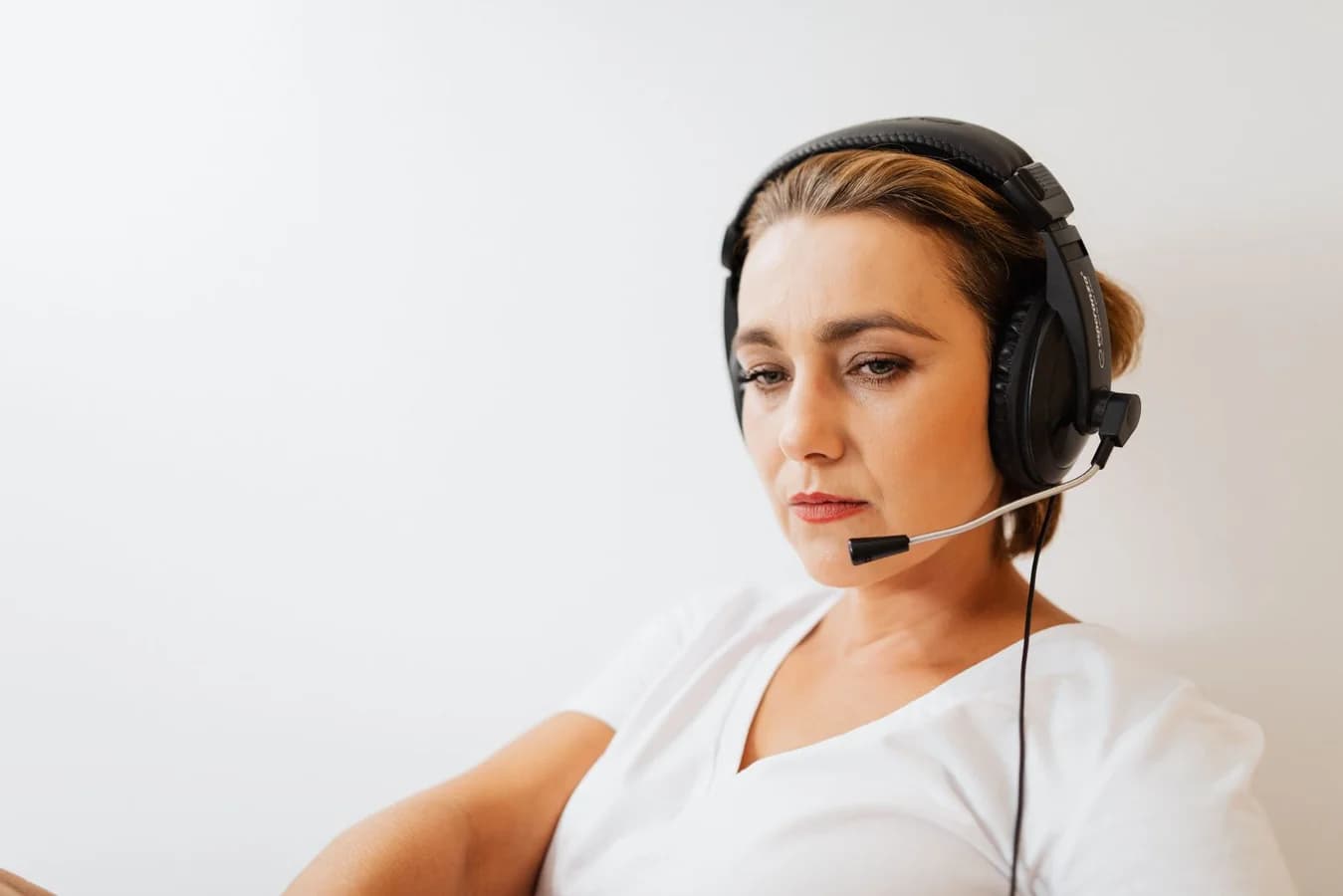 Support agent wearing a headset against a plain background